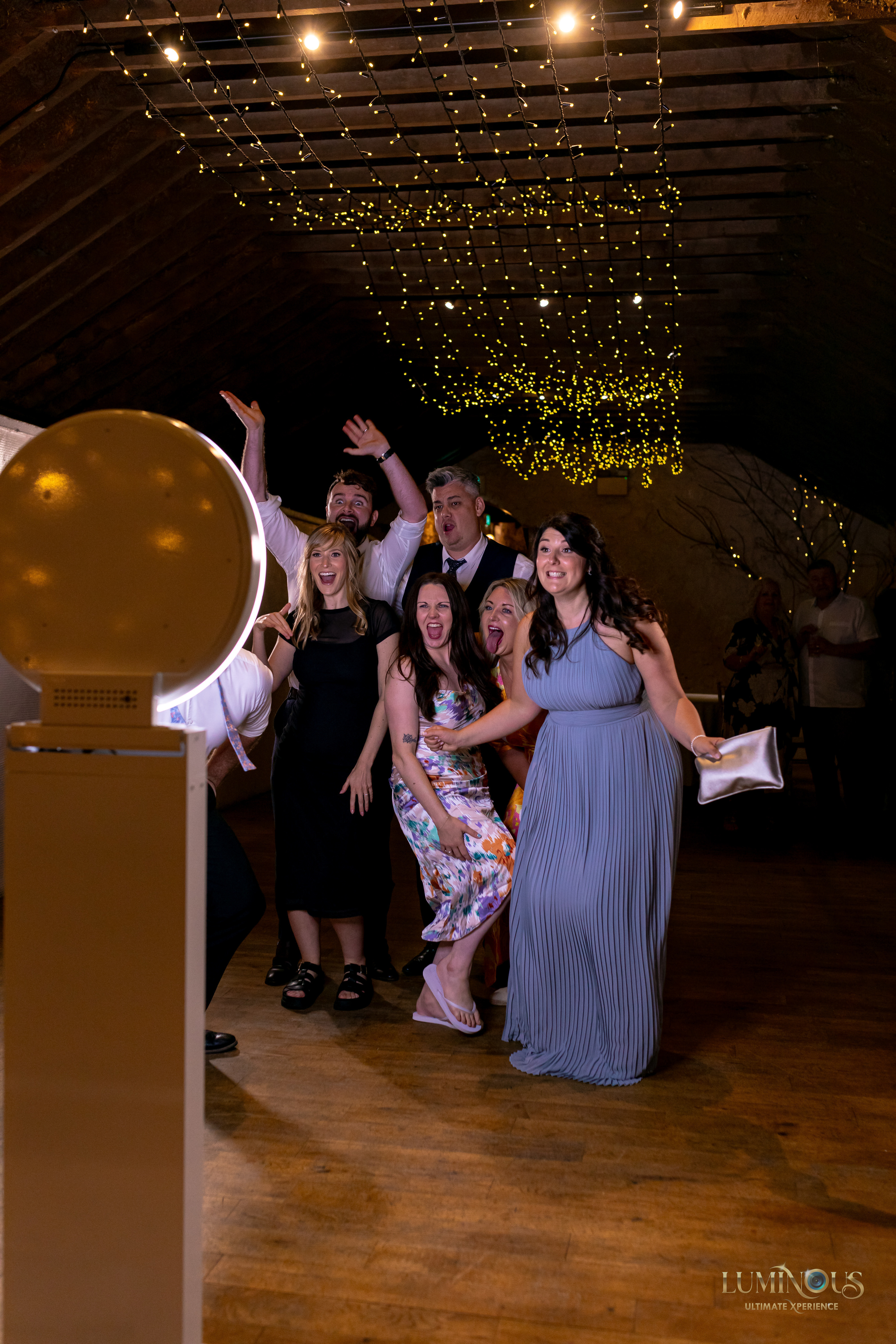 A group of wedding guests having fun posing for photos on thhe Mobi Aura booth